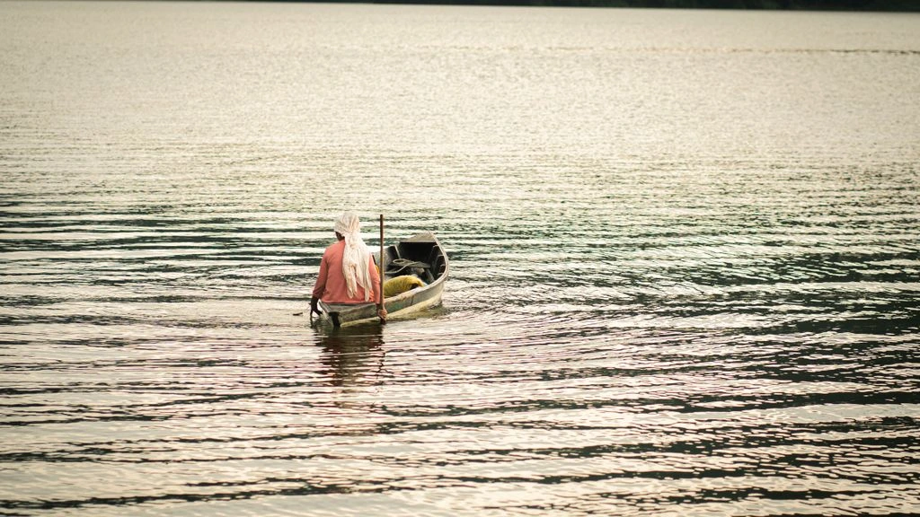 An elderly fisherman mends nets at sunrise