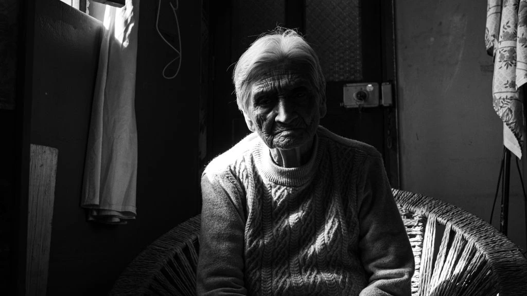 An elderly woman watches a film in a darkened cinema